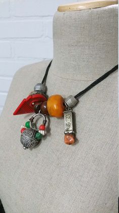 "Lovely Moroccan Berber silver hair ring, silver fibula cap & coral and a resin amber bead on black leather necklace no 3. Easy to wear necklace with a lovely old silver Berber hair ring with little beads, resin amber bead, ceramic bead, old silver fibula cap with coral and a red glass pendant. This is number 3 of 7 necklaces, they are all different so check the pictures what necklace you like best! They make a wonderful gift. All pendants are strung on a black multi strand leather necklace. Silver Bohemian Beaded Necklaces With Bead Caps, Silver Bohemian Beaded Necklace With Bead Caps, Red Bohemian Necklace With Lobster Clasp, Bohemian Red Beads, Gems, And Cabochons, Black Leather Necklace, Bohemian Red Round Beads, Gems And Cabochons, Wear Necklaces, Hair Rings, Amber Beads