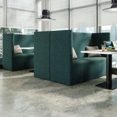 an office cubicle with two green couches and a table in front of it