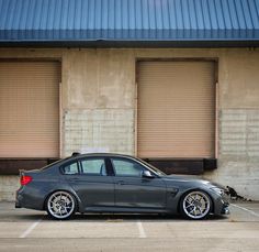 a grey car parked in front of a building next to a parking lot with closed doors