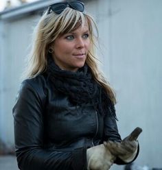 a woman in black jacket and gloves holding a cell phone