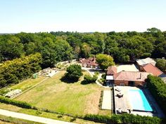 an aerial view of a house with a swimming pool in the foreground, surrounded by trees