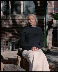 a woman sitting on a bench in front of a brick building