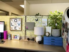 a desk with a computer, lamp and pictures on it