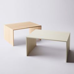 two wooden tables sitting next to each other on a white surface in front of a wall