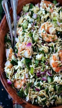 a wooden bowl filled with rice and shrimp salad