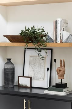 a shelf with some books and vases on it next to a bookcase filled with books