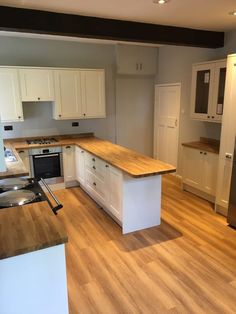 an empty kitchen with wooden floors and white cabinets