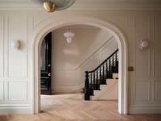 an arched doorway leading to a hallway with white walls and wood floors, along with a black door