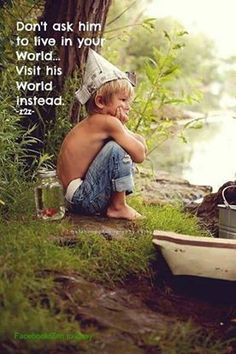 a young boy sitting on the ground next to a tree