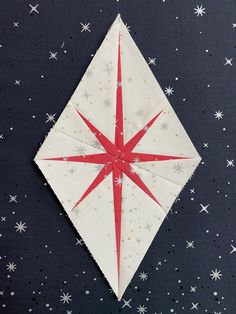 an origami star on a black surface with stars in the sky behind it