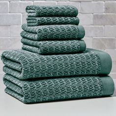 stack of green towels in front of a brick wall with white bricks on the side