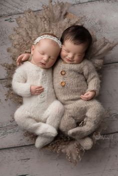 two baby dolls are laying next to each other