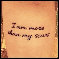 a tattoo saying i am more than my scars on someone's left leg,