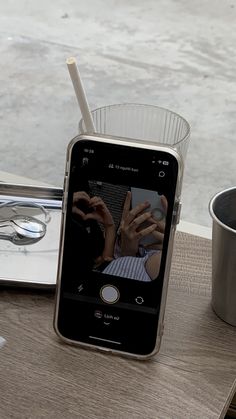 a cell phone sitting on top of a wooden table next to a cup and spoon