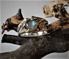 This ring tells a fantastic story as its motifs, oxidation, and stone give it a magical allure!  Made of sterling silver mounted with a labradorite stone that has amazing blue flashing. Inspired by the stone, I first sculpted the ring in wax, then it was cast in sterling silver (lost wax technique.) Each ring is crafted ergonomically to be comfortable. You will also be able to appreciate and sense the high-quality solid silver that I use. Labradorite: 5mm I make each ring separately, so just let me know if you want another design, size or stone, and I'll do it, but each stone is unique and different! Please contact me with any questions. Labradorite : Labradorite is a feldspath, generally blue-grey, with a partly iridescent surface.   It is named after the region of Labrador in Canada, whe Mystical Gemstone Rings For Collectors, Mystical Collectible Gemstone Rings, Handmade Magical Silver Rings, Hand Forged Silver Spiritual Ring, Nature-inspired Untreated Silver Rings, Unique Sterling Silver Moonstone Ring, Unique Opal Ring For Jewelry Making, Unique Hand Forged Moonstone Open Ring, Mystical Silver Opal Ring