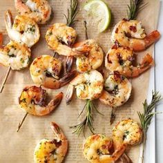 grilled shrimp skewers with lemon wedges and rosemary garnishes