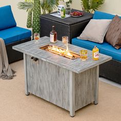 a fire pit sitting on top of a wooden table next to blue couches and potted plants