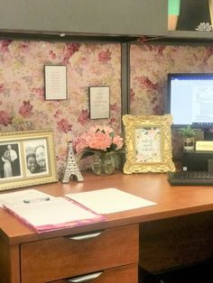 a desk with a laptop, flowers and pictures on the wall next to an open file cabinet