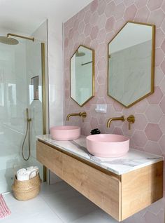 two pink bowls are sitting on the counter in this bathroom with hexagonal tiles