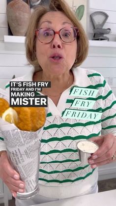 a woman holding a bucket full of fried fish and chips in front of her face