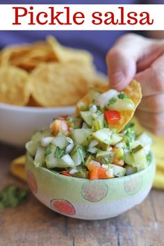 a person scooping up some food from a bowl with tortilla chips in it