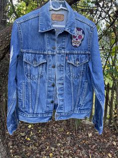 Here's a custom jean jacket made from a vintage Levi's jacket.  I hand studded the back and applied patches to accompany the look. If you want to stand out in a unique one of a kind jacket that is timeless and fresh, look no further!! Don't miss out. Fall Denim Jacket With Embroidered Patch For Streetwear, Fitted Embroidered Denim Jacket For Streetwear, Fall Festival Denim Jacket With Patches, Denim Outerwear With Patches For Festival, Vintage Levis Jacket, Custom Jean, Custom Jean Jacket, Patch Jacket, Custom Jeans