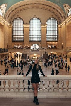 a woman is standing in the middle of a train station