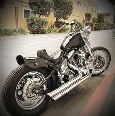 a black motorcycle parked on the side of a road next to a parking lot with buildings in the background