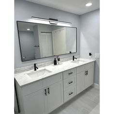 a bathroom with double sinks and large mirrors