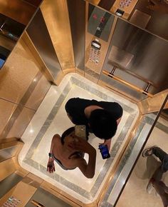 a woman is taking a selfie in the mirror on top of a lift at an elevator