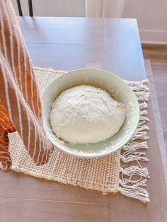 a bowl of bread sitting on top of a table next to a person's leg