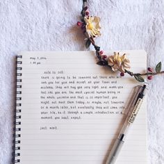 an open notebook with a pen and flower on it