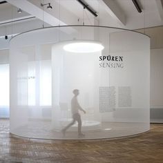 a person walking past a display in a room with white walls and wood flooring