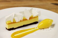 a white plate topped with a piece of cake and a yellow spoon next to it