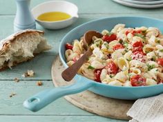 a blue bowl filled with pasta salad next to bread