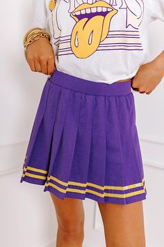 - Cheer on your team in this cute pleated skort! Featuring bold jersey-style accent stripes, it's perfect for showing off a sporty-chic vibe on game day. Crisp pleats make it perfect for letting your team spirit shine. Rally your friends and get ready to celebrate in style with this adorable piece. - Stretchy pleated material - Built-in stretchy shorts - An elastic waistline - Jersey-style sequined accent stripes at the bottom of the skirt - A flattering silhouette that ends in a pleated upper-t Purple Skort For School, Purple Casual Skort For School, Sporty Pleated Skort For School, Sporty Purple Skort For Summer, Preppy Cotton Mini Tennis Skirt, Casual Tennis Skirt With Elastic Waistband For Cheerleading, Sporty Mini Tennis Skirt For School, Purple Cotton Bottoms For School, Sporty Spring Skort For School