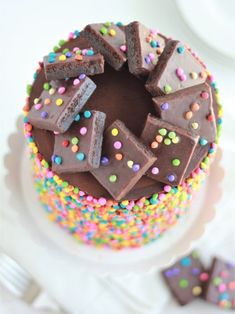 a cake with chocolate frosting and sprinkles sitting on a white plate