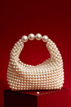 Crafted with hand-selected off-white pearls, this bag is the perfect statement piece for any occasion. And hand-crafted by our skilled artisans. Style our Zia Pearl purse to make a lasting impression and shine at every event. Dimensions (LxB): 3.25"x 7" (8 cm x 18 cm) Base(LxB): 4"x6.5" (10 cm x 17 cm) Handle drop: 3.5" (9 cm) Women's Bag By Pattern, American Casual, Pearl Bag, Evening Purse, Pearl Collection, Wedding Bag, Beaded Bags, Stylish Bag, White Beads