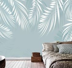 a bedroom with a bed and wallpaper that has white palm leaves on the blue background