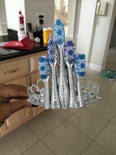 a person holding two toothbrushes in their hand and some other things on the counter