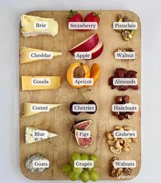 a wooden cutting board topped with lots of different types of cheeses and fruits on it