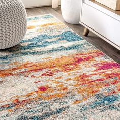 an area rug with multicolored paint splattered on it in a living room