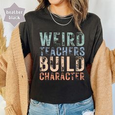 Holiday Shipping Deadline: December 9th Orders placed after December 9th may not arrive by 12/24 Embrace the unique charm of educators with our "Weird Teachers Build Character" Shirt, a playful addition to any teacher's wardrobe. This retro teacher tshirt is not only a humorous statement piece but also a thoughtful gift for those who appreciate the quirks that make teaching memorable. Perfect for Teacher Appreciation or casual Fridays, this funny teacher t-shirt celebrates the fun side of educat Teacher Outfits Big Bust, Teacher Shirts Designs Funny, Funny Black Tops For End Of School Year, School Spirit Letter Print Top, Casual Tops With Funny Text For Teaching, Black Top With Text Print For Teaching, Black Text Print Top For Teaching, Teacher Shirts Funny Missy Lulu’s, Funny Teacher Shirts Zazzle