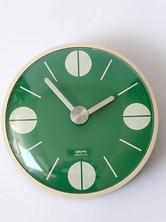 a green clock with white numbers on the face and hands is shown against a white background