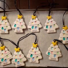 twelve ceramic christmas tree ornaments are on a baking sheet, with string attached to them