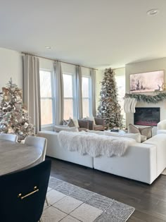 a living room filled with furniture and a fire place covered in christmas tree decorations on top of a hard wood floor