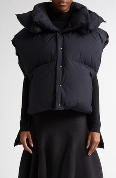 Oversizing and asymmetry serve function as well as fashion purposes for this down puffer vest. A drop-tail hem provides protection from the cold to the upper thighs, with the cropped front warming your core without obscuring the outfit beneath. Extended shoulders and a voluminous hood ensure an on-brand silhouette for the style. 23" front length; 34" back length (size 12) Front snap closure Stand collar Fixed hood Front welt pockets Drop-tail hem Side slits with snap closures Lined, with 90% dow Fitted Nylon Vest Outerwear, Fitted Nylon Winter Vest, Fitted Sleeveless Outerwear With Padded Collar, Puffer Vest, The Outfit, Stand Collar, Welt Pockets, Snap Closure, Clothing Items