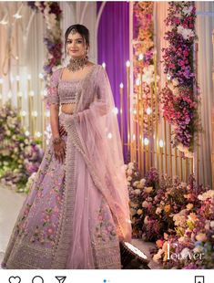 a woman in a pink lehenga standing next to flowers