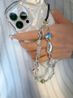 a woman's hand holding a cell phone and some bracelets