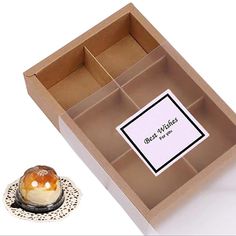 an open box with a pastry in it next to a small cupcake on a plate